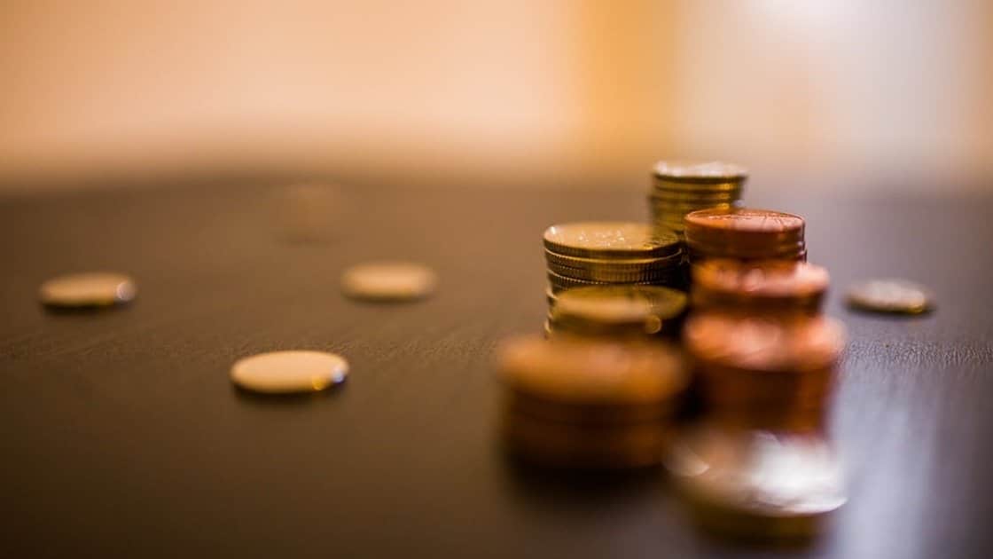 Stacks of coins of varying sizes and colors on a dark surface with a blurred background.